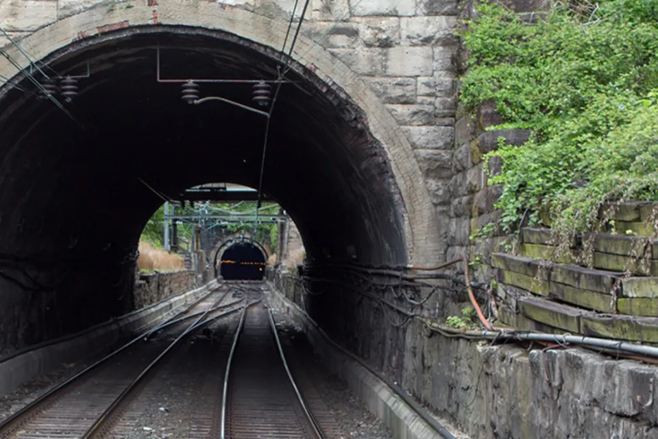 View into gray stone train tunnel with visible opening on other side